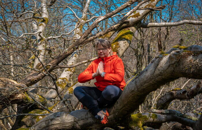 Frau sitzt im Baum in der Yogaposition zum Mantra