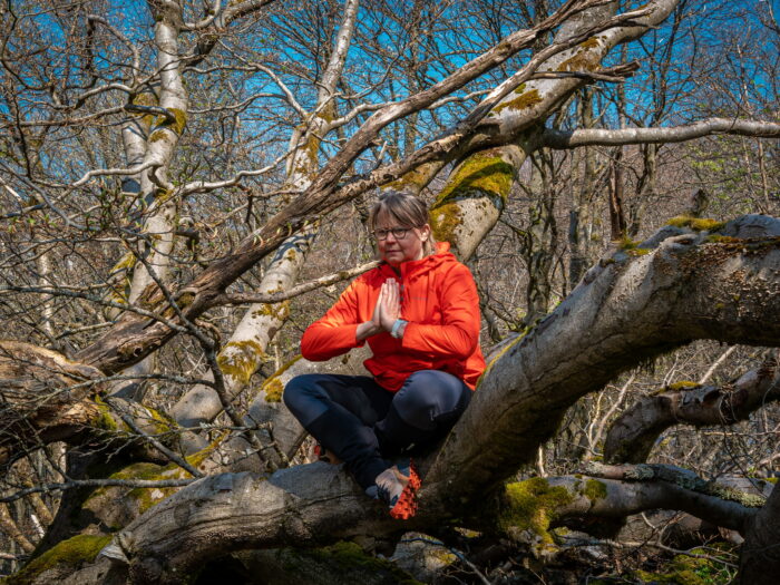 Frau sitzt im Baum in der Yogaposition zum Mantra